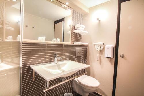 a bathroom with a toilet, sink and mirror at Hôtel Inn Design Resto Novo Sablé in Sablé-sur-Sarthe