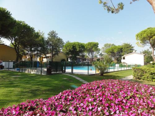 a park with pink flowers and a swimming pool at Villaggio Azzurro - Ville in Bibione