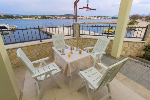 a table and chairs on a balcony with a view of the water at Riva in Krapanj