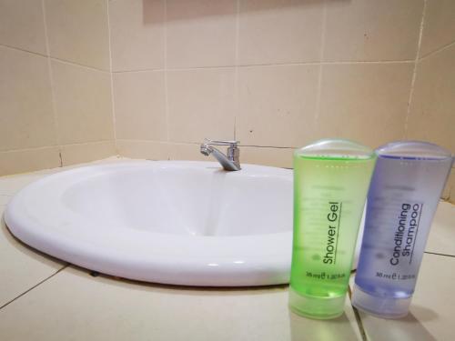 a bathroom sink with two plastic cups next to it at Clover Hotel Port Dickson in Port Dickson