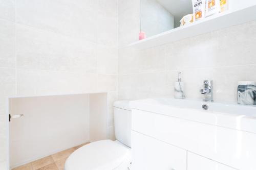 a white bathroom with a toilet and a sink at Lovely Studio Flat in West Kilburn by Queen's Park in London