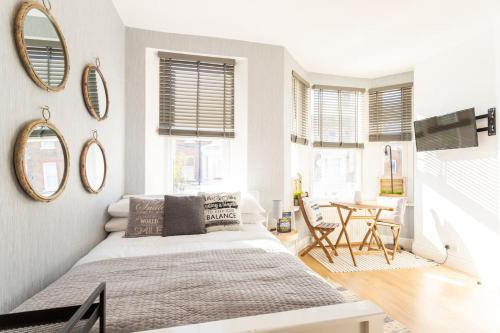 a bedroom with a bed and a table and mirrors at Lovely Studio Flat in West Kilburn by Queen's Park in London