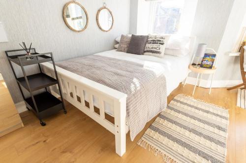 a bedroom with a white bed and a mirror at Lovely Studio Flat in West Kilburn by Queen's Park in London