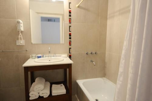 y baño con lavabo, ducha y bañera. en Corzuelas Aparts - Mina Clavero en Mina Clavero