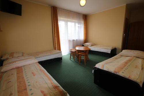 a room with three beds and a table and a window at Dom Wypoczynkowy Tulipan in Zakopane