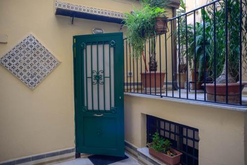 een groene deur aan de zijkant van een gebouw met planten bij Millimetro in Palermo