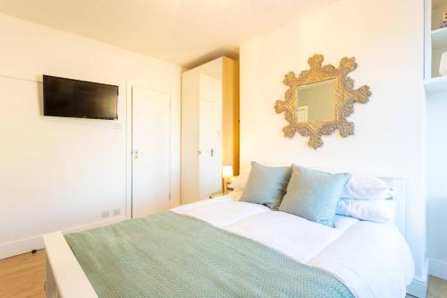 1 dormitorio con cama y espejo en la pared en Chic Studio Flat in West Kilburn near Queen's Park, en Londres