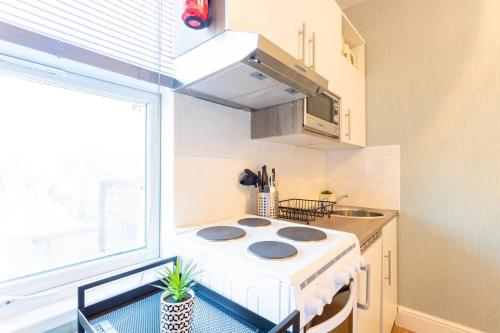 a small kitchen with a stove and a window at Chic Studio Flat in West Kilburn near Queen's Park in London