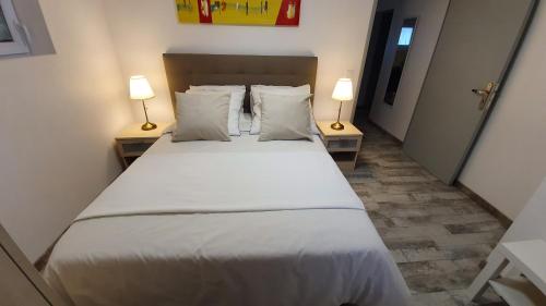 1 dormitorio con 1 cama blanca grande y 2 lámparas en "LE TRAMWAY" Appartement 150m gare des Aubrais en Fleury-les-Aubrais