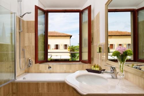 a bathroom with a sink and a tub and two windows at Villa Sabolini in Colle Val D'Elsa