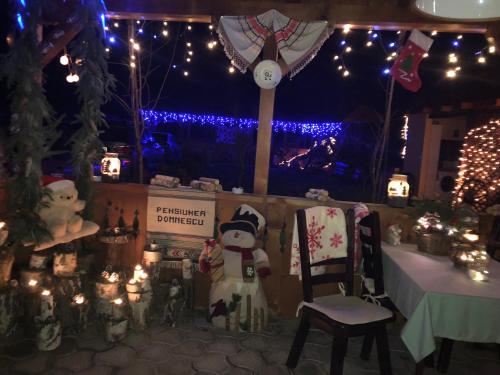 a room with a table with a clock and christmas lights at Pensiunea Domnescu in Sălişte