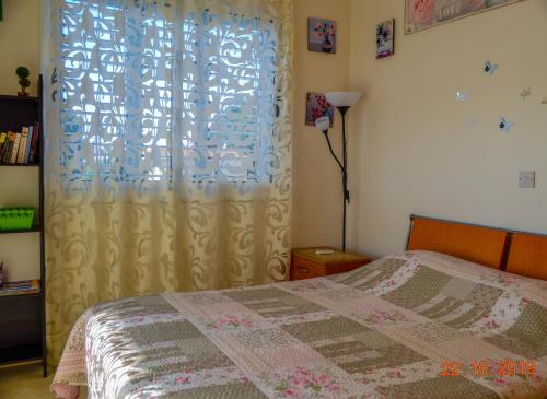 a bedroom with a bed and a window with a curtain at Enjoy the silence apartments in Paphos