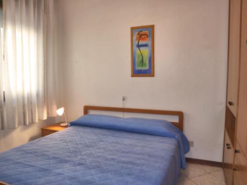 Un dormitorio con una cama azul y una pintura en la pared en Viviana, en Lignano Sabbiadoro