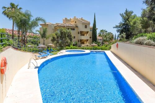 a swimming pool in front of a villa at Elviria Apartment in Marbella