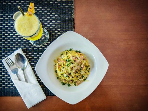 a bowl of pasta and a drink on a table at Grand Mirah Boutique Hotel in Denpasar