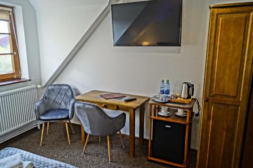 a room with a desk and two chairs and a television at Pensjonat Miejski in Zgorzelec