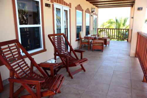 a porch with rocking chairs and tables on a balcony at Belizean Nirvana in Placencia Village