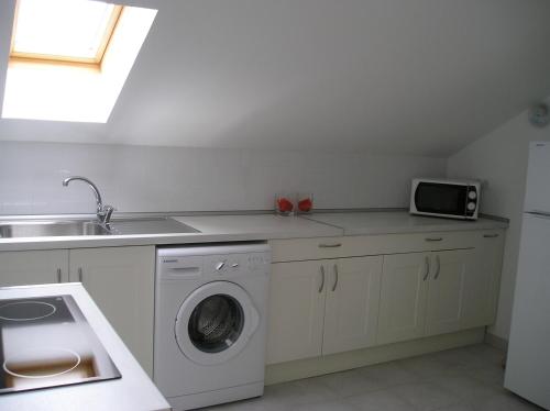 a kitchen with a washing machine and a sink at Las Navedas in Santibáñez de Villacarriedo