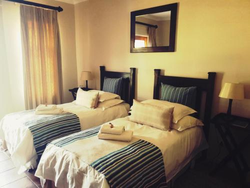 two beds in a hotel room with towels on them at Ash River Lodge in Clarens