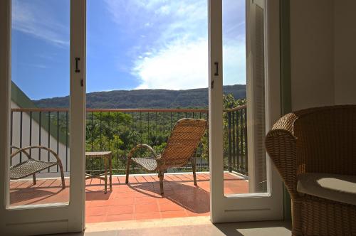 an open door to a balcony with chairs and tables at Pouso Alforria in Tiradentes