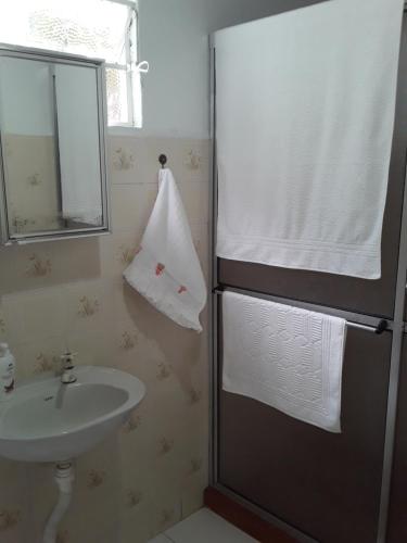 a bathroom with a sink and a shower with a mirror at Suíte bem localizada. in Campos do Jordão