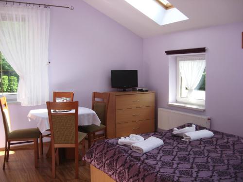 1 dormitorio con cama, mesa y TV en Zajazd Idylla, en Sierakowice