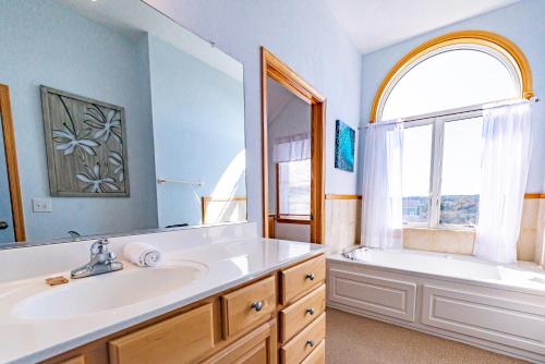 a bathroom with a sink and a tub and a window at By the Sea in Kill Devil Hills