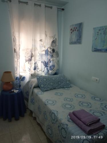 1 dormitorio con 1 cama y 1 mesa con lámpara en Como en casa, en Alicante
