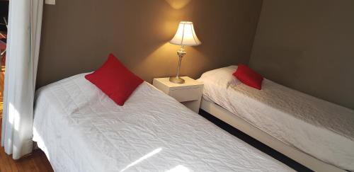 a bedroom with two beds with red pillows and a lamp at Satya Suites & Portal San Angel Flats in Mexico City