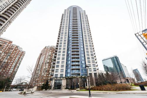 a tall white building in a city with tall buildings at PlanURstay - Luxury Suites Mississauga Downtown in Mississauga