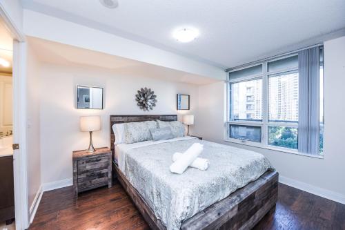 a bedroom with a large bed and two windows at PlanURstay - Luxury Suites Mississauga Downtown in Mississauga