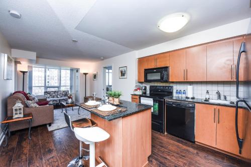 a kitchen with wooden cabinets and a living room at PlanURstay - Luxury Suites Mississauga Downtown in Mississauga