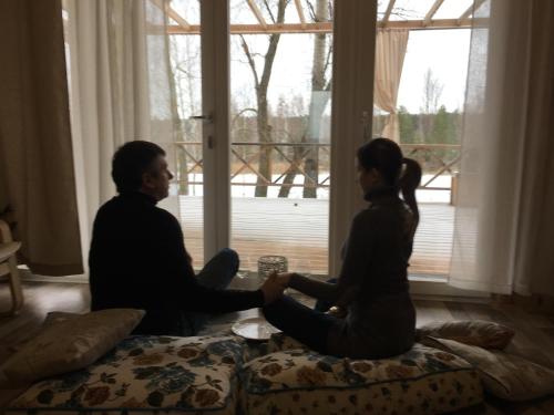 a man and woman sitting on a bed in front of a window at Relax villa Poduzska in Sinyak