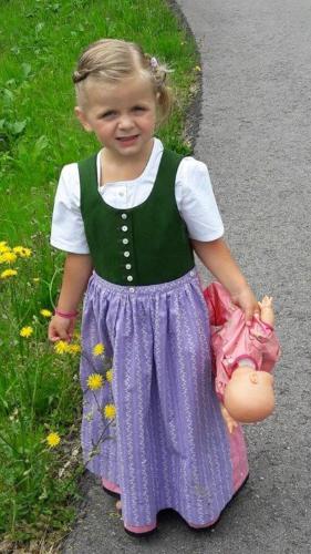 a little girl in a dress holding a toy at Berghaus Schäfer in Faschina