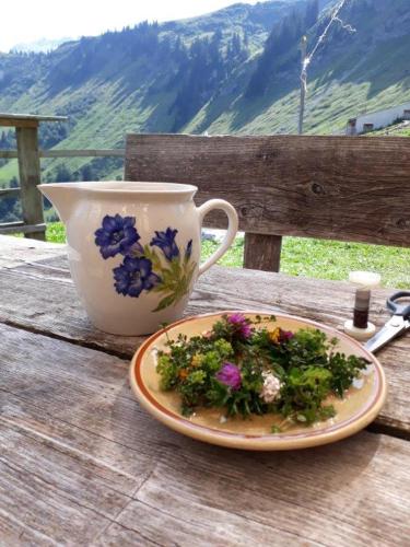 a plate of flowers on a table next to a cup at Berghaus Schäfer in Faschina