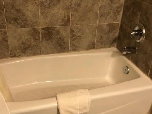 y baño con bañera blanca y pared de azulejos. en Economy Inn Alamogordo, en Alamogordo