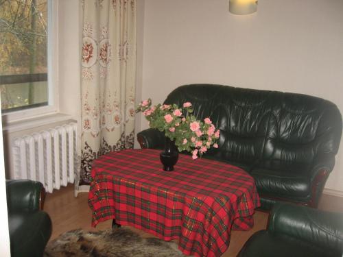 a black leather couch with a table with a vase of flowers at Upmaļi in Tērvete