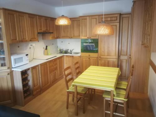 une cuisine avec des placards en bois, une table jaune et des chaises dans l'établissement Promenade Apartman, à Balatonlelle