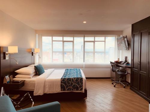 a bedroom with a bed and a window and a desk at Hotel Dann Cali in Cali