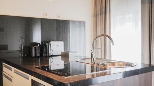 a kitchen with a sink and a counter top at Amosa Liège City Centre Hotel in Liège