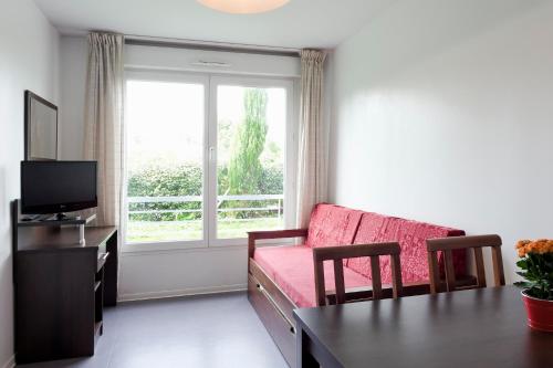 - un salon avec un canapé, une table et une fenêtre dans l'établissement Residhotel Les Hauts d'Andilly, à Andilly
