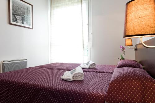 a bedroom with a purple bed with towels on it at Residhotel Les Hauts d'Andilly in Andilly