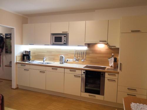 a kitchen with white cabinets and a sink and a microwave at An der Mühle in Tux