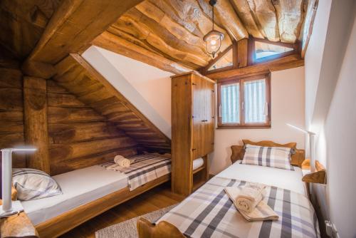 two beds in a attic bedroom with wooden ceilings at Baranjska eko drvena kuća in Kopačevo