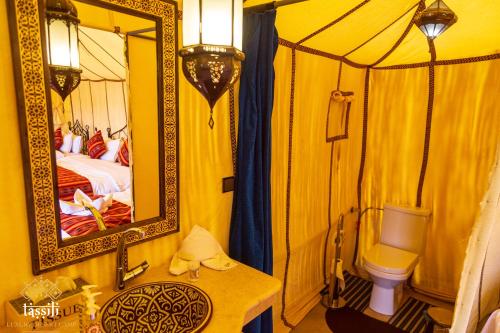 a yellow room with a bed and a mirror at Tassili Luxury Desert Camp in Merzouga