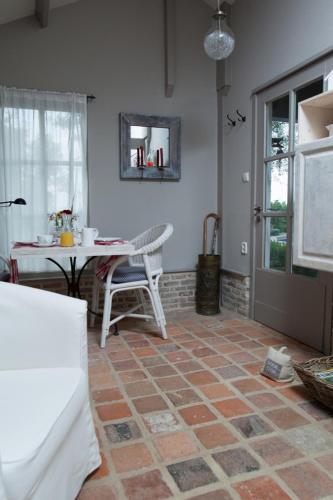a living room with a tiled floor and a table at In d'Ouwe Vlaamse Schuur in Ossendrecht