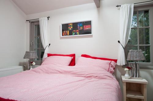 a bedroom with a pink bed with red pillows at In d'Ouwe Vlaamse Schuur in Ossendrecht