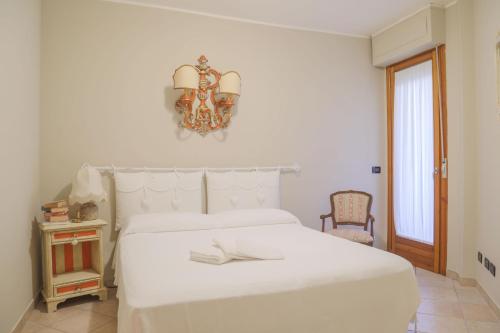 ein weißes Schlafzimmer mit einem weißen Bett und einem Kronleuchter in der Unterkunft Grazioso appartamento nel centro della Toscana in Poggibonsi