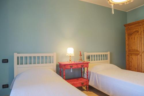 a bedroom with two beds and a red table with a lamp at Grazioso appartamento della Toscana in Poggibonsi