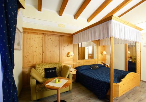 um quarto com uma cama, um sofá e uma mesa em Alexander Hotel Alpine Wellness Dolomites em Molveno